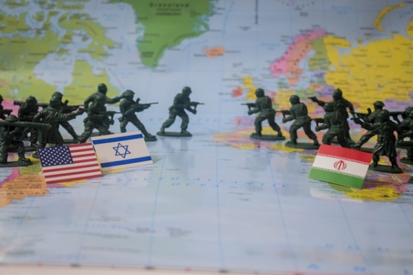 Miniature di soldati su una mappa del mondo con le bandiere di Iran, Israele e Stati Uniti.