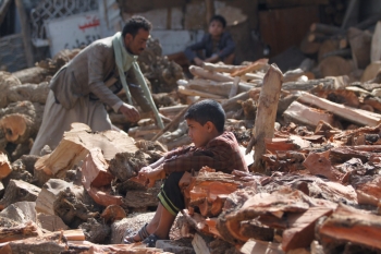 un bambino yemenita seduto tra le macerie di Sana’a.