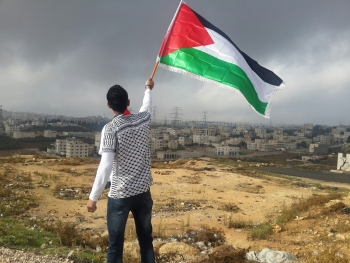 Un uomo che sventola la bandiera palestinese in Giordania