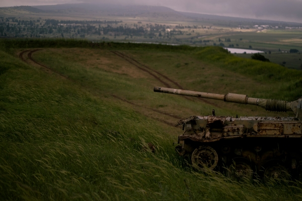 military tank crossing a grassy field 