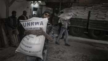 Un rifugiato palestinese porta un pacco di farina al centro di distribuzione di derrate alimentari dell'UNRWA