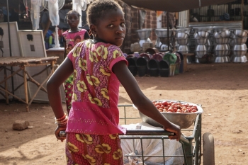 Giovane ragazza trasporta prodotti alimentari nel mercato di Tougan, Burkina Faso