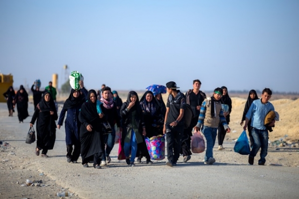 Group of migrants walking along a dirt road.
