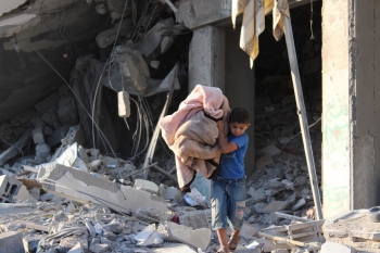 Un bambino esce dalla sua casa distrutta a Gaza, stringendo una coperta tra le braccia