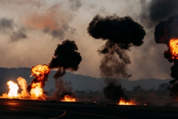 A dramatic scene featuring explosions and thick black smoke rising outdoors