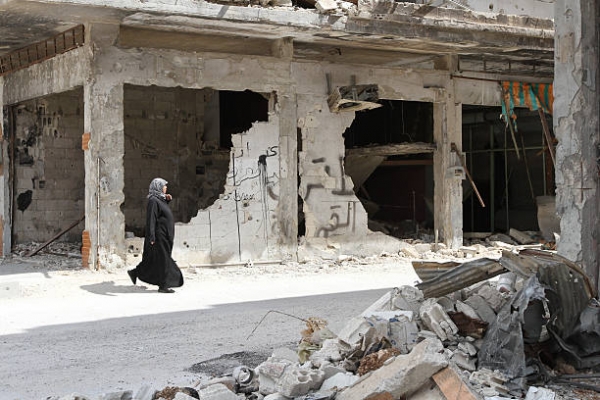 Una donna che cammina tra le case nella citt&agrave; di Homs