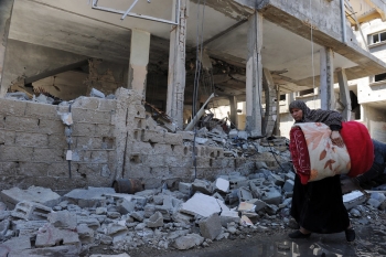 A Palestinian woman beside a destroyed building in Gaza