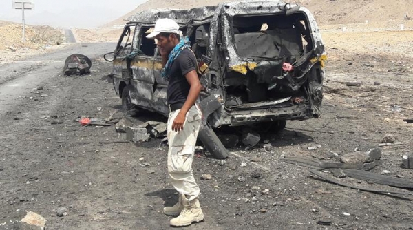 Soldier talks on the phone as he stands at the site of a suicide car bomb attack in Mukalla, Yemen 