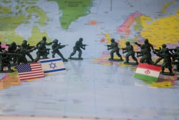 Miniature soldiers on a world map with the flags of Iran, Israel, and the United States.