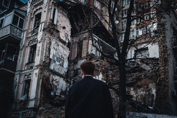 Uomo in piedi davanti a un edificio distrutto in Ucraina