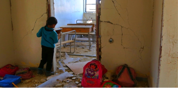 Un bambino siriano guarda l&rsquo;aula di scuola distrutta nella citt&agrave; di Ulaya, vicino Damasco 