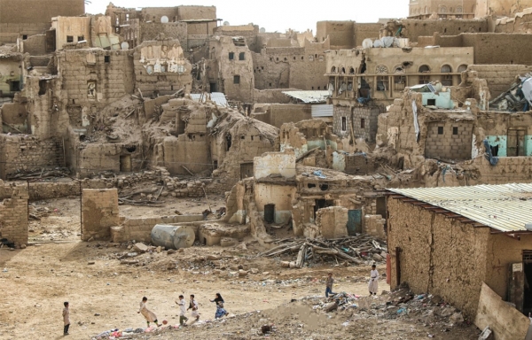 Children play football against a backdrop of destroyed houses in northwest Yemen