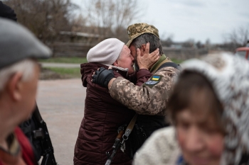 An old woman hugs a soldier