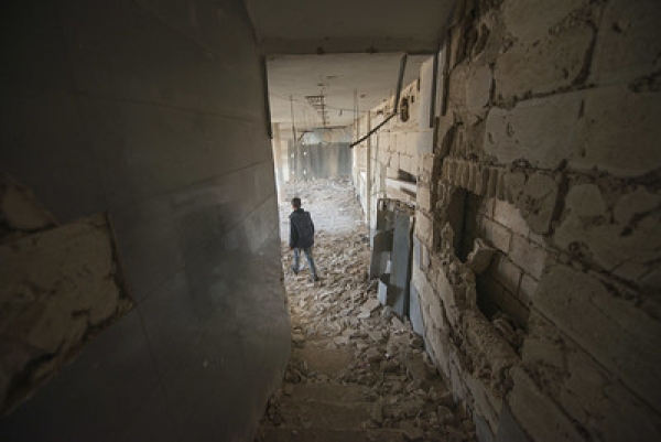 Un bambino cammina tra le macerie all'interno di un edificio colpito da un attacco aereo, Siria, 13 novembre 2018