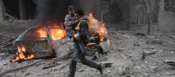 A Syrian paramedic carries an injured child
