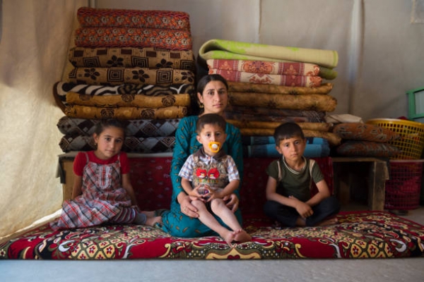 Una giovane donna yazidi siede con i suoi tre figli all'interno di una tenda nel campo di Sharya, nel nord dell'Iraq.