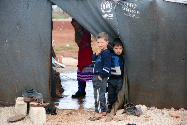 A group of Syrian refugees standing outside a UNHCR shelter.