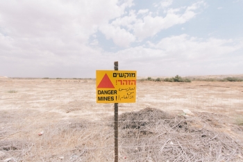 Sign warning of mines in front of a filed 