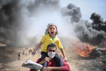 Uomo e bambino che protestano tra le bombe