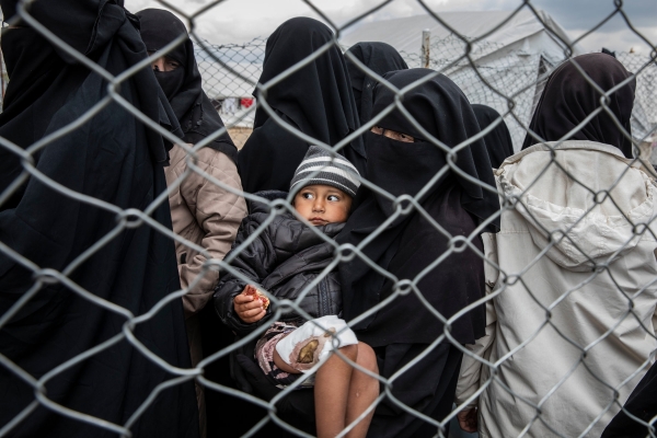 A woman carries an injured boy amidst group of females in a Syrian camp 