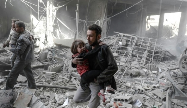 Men evacuate children from the rubble of destroyed buildings