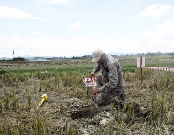 Tecnico di Explosive Ordnance Disposal mentre scava per verificare la presenza di munizioni cluster