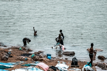 Un gruppo di persone in piedi su una spiaggia accanto ad uno specchio d&rsquo;acqua