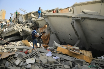Un gruppo di persone tra le macerie di un edificio bombardato.