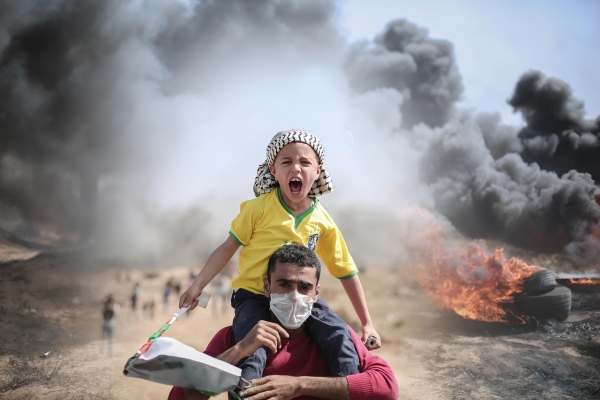 Un uomo e un bambino fuggono tra le macerie e gli edifici danneggiati a Gaza durante il conflitto.