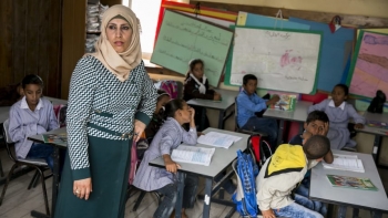 Un&rsquo;insegnante guarda fuori mentre i bambini parlano tra di loro nella Tyre School