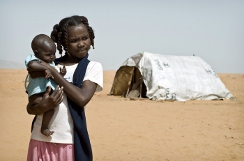 Una bambina che tiene in braccio un neonato, Sudan, 2011.