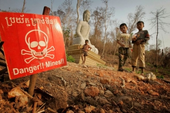 Children play near a landmine warning sign in New Village Border, Cambodia. 