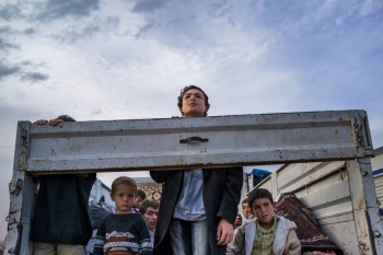 Syrian Kurdish refugees look out from the back of a truck as they enter Turkey from the town of Kobane, Syria. 