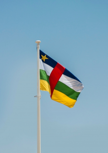 The national flag of the Central African Republic flies in the sky.