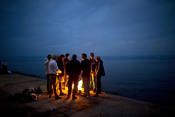 Afghan refugees gather around a fire to warm themselves after arriving on a dinghy from the Turkish coast to the northeastern Greek island of Lesbos