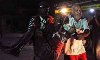 Un uomo ferito è portato via dal luogo dell&#039;attacco nel centro di Mogadiscio. 