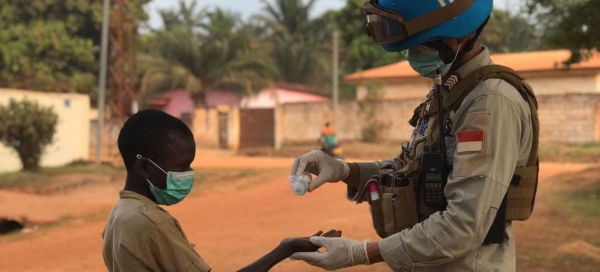 A peacekeeper sanitizing a child’s hand
