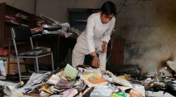 Afghan boy collects books among the rubble of a school in Nangarhar province, Kabul 