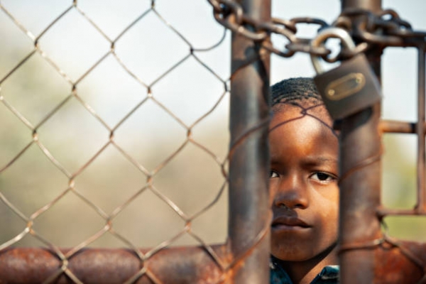 Bambino africano dietro una rete metallica