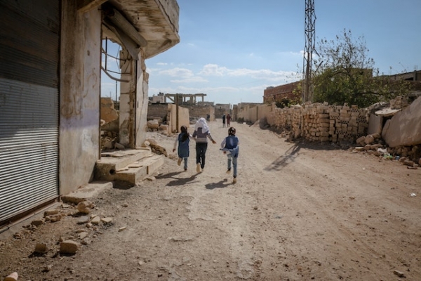 Dei bambini corrono tra le macerie a Idlib, Siria
