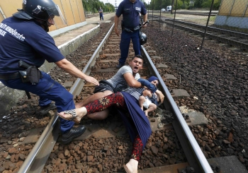 Un agente di polizia ungherese nell&#039;atto di bloccare dei profughi siriani