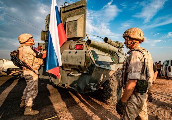 Russian military forces stand near an armored personnel carrier in Syria