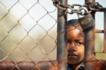 African child behind a metal fence