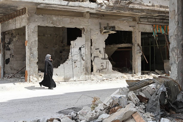 Una donna che cammina tra le case nella città di Homs
