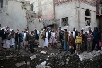 Un gruppo di Yemeniti di fronte alle rovine di alcuni palazzi