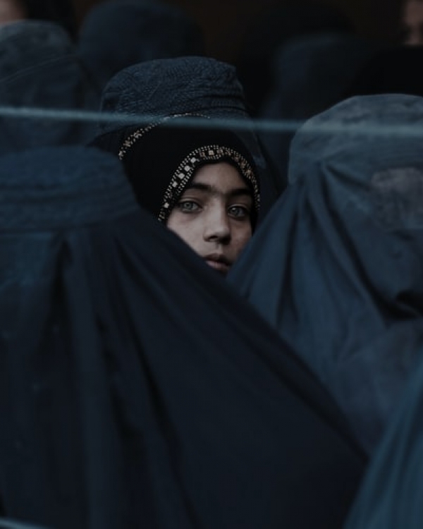 A girl looks on among Afghan women lining up 