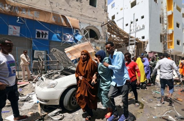 Civilians walk through an attack scene in Mogadishu, Somalia