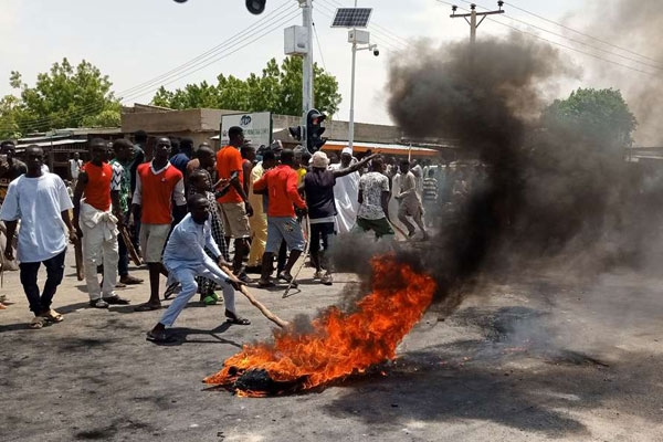 I manifestanti a Maiduguri bloccano la strada e rimangono vicino ad un pneumatico in fiamme mentre richiedono la fine della milizia CJTF, 30 giugno 2019. 