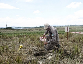 Explosive Ordnance Disposal technician  digging around the marked location to check for cluster munitions