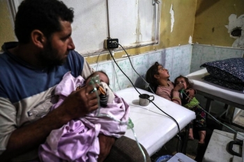 Un padre e una madre tengono i loro bambini malati in un ospedale improvvisato nel Ghouta orientale in Siria, lunedì scorso, gennaio 22